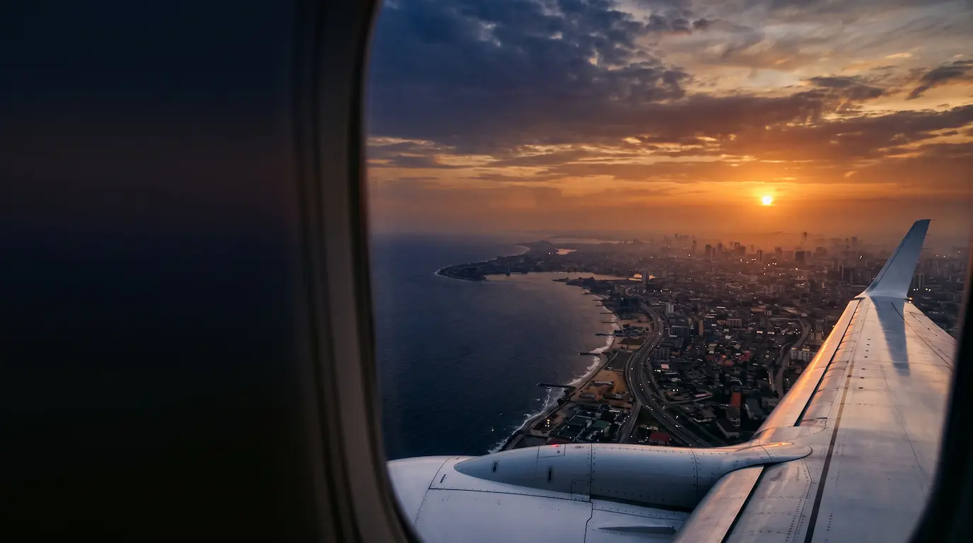 Aircraft wing above the West African coastline at sunset
